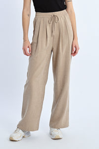 Person wearing beige wide-leg pants on a white background