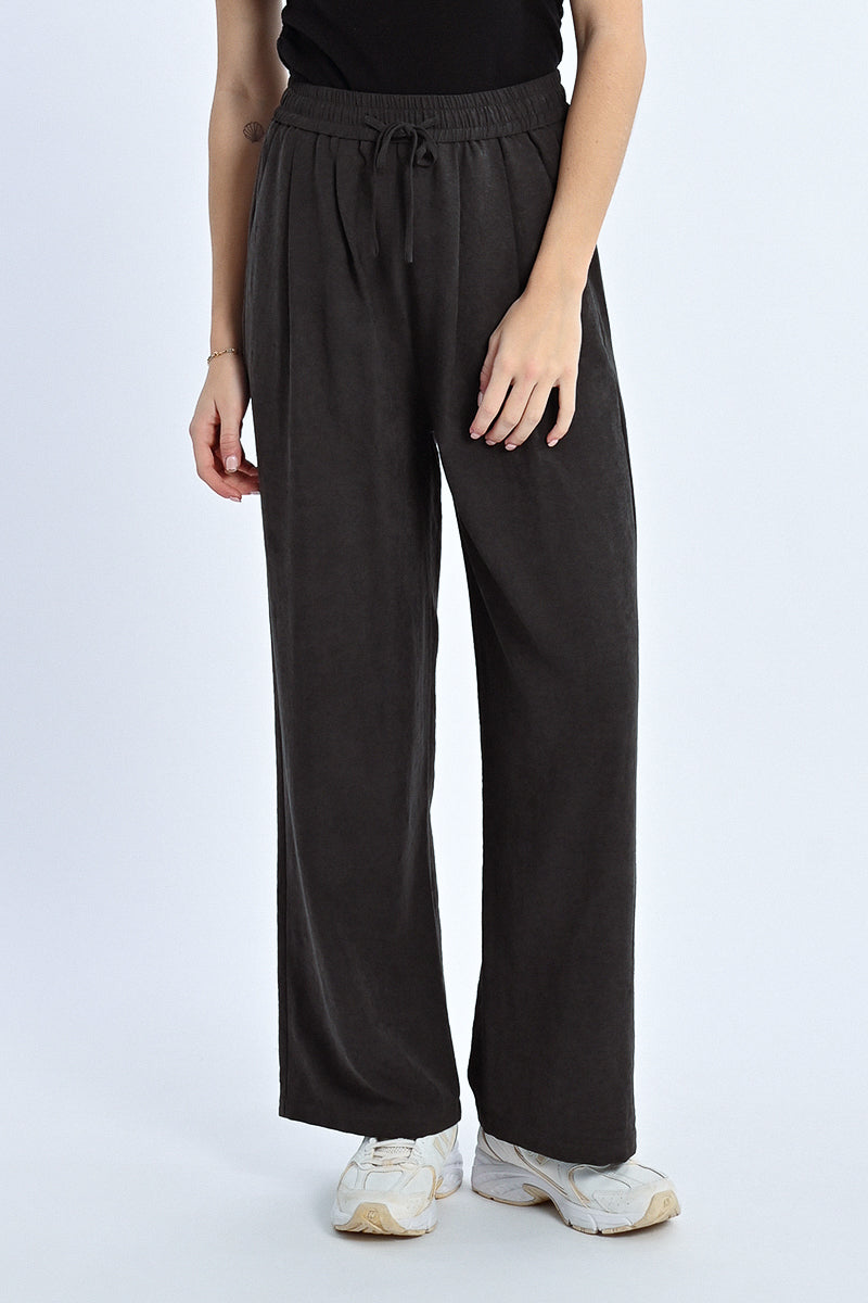 Person wearing black wide-leg pants on a white background